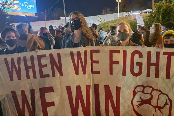 Union members rallying with a sign that says "When we fight, we win".