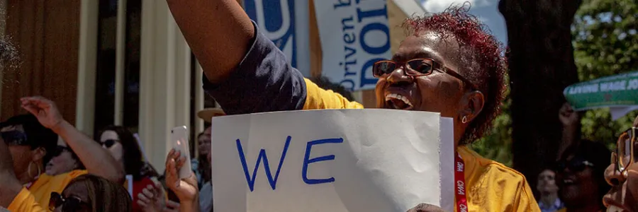 Miss Diane at a rally holding a sign that says We Deserve Better