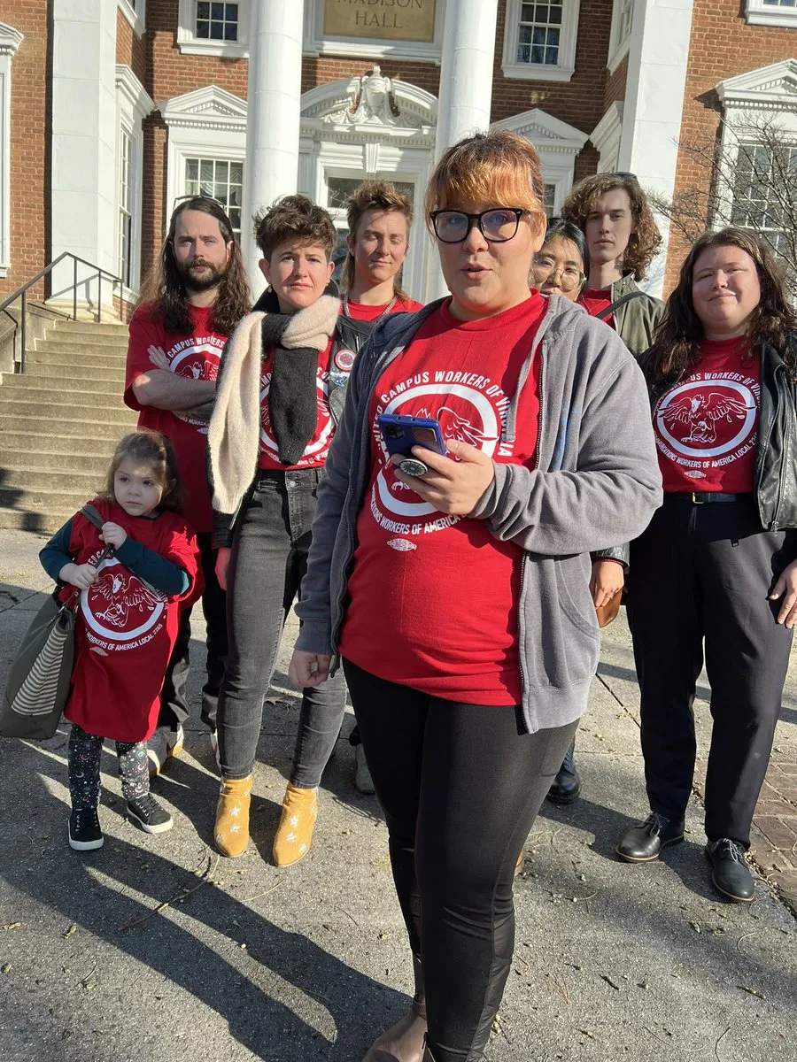 Delegation of UCWVA workers wearing bright red t-shirts standing in front of a building with white columns. 